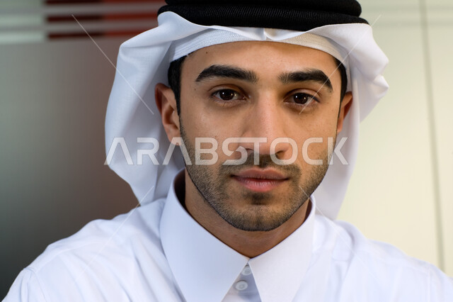 الأناقة و الاهتمام بالمظهر الخارجي ، صورة مقربة لوجه شاب عربي إماراتي خليجي يرتدي الغترة و الثوب الإماراتي التقليدي ويبتسم  , إيماءات وجه تدل على الثقة بالنفس ،  نظرات مليئة بالطموح والشغف بالعمل , بيئة العمل الإماراتي . 
