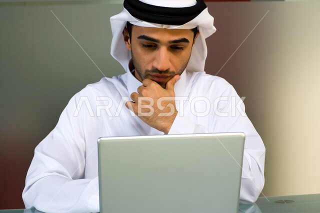 الوسامة والأناقة والثقة بالنفس  ، شاب عربي إماراتي خليجي يرتدي الغترة و الثوب الإماراتي التقليدي ويقوم باستخدام الحاسوب المحمول , إنجاز مهام العمل اليومية،  تحقيق أهداف الشركة من خلال التفاهم و التعاون بين الموظفين, إيماءات وجه تدل على الشغف بالعمل  . 