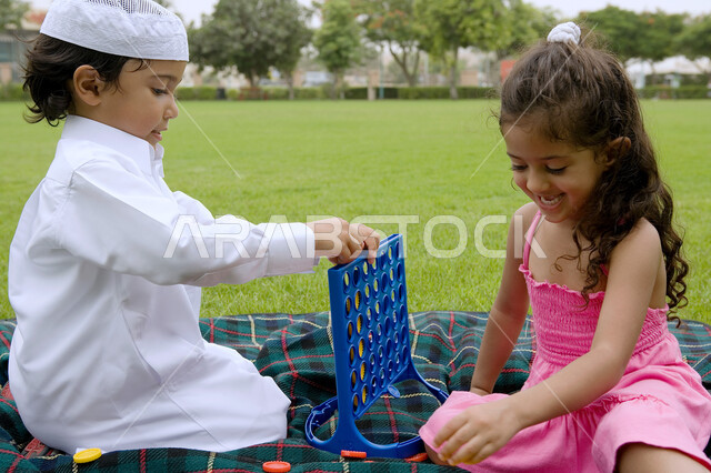 تنمية المهارات الفكريه والذهنيه، أخوان عربيان خليجيان اماراتيان يتنافسان للفوز بلعبه اربع تربح، الاستفاده من أوقات الفراغ في اللعب بالألعاب المفيده، فضاء أوقات ممتعة في الهواء الطلق في إحدى الحدائق العامه في الامارات، ايماءات التركيز والتفكير.