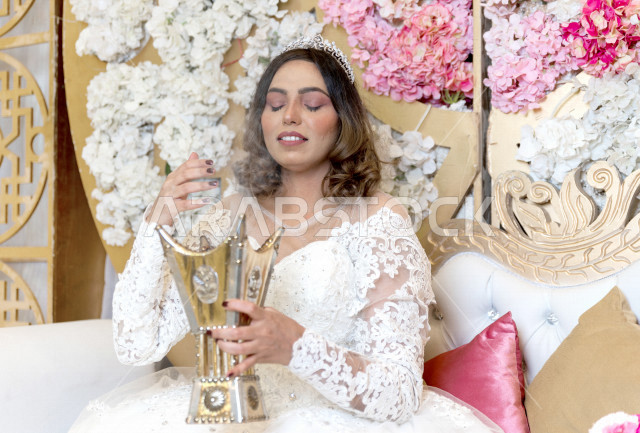عروسة سعودية خليجية تجلس على الكوشة  ،تقوم بالتطيب بالبخور و العود ، ترتدي بدلة الزفاف البيضاء ، ليلة العمر ، مناسبات و أفراح