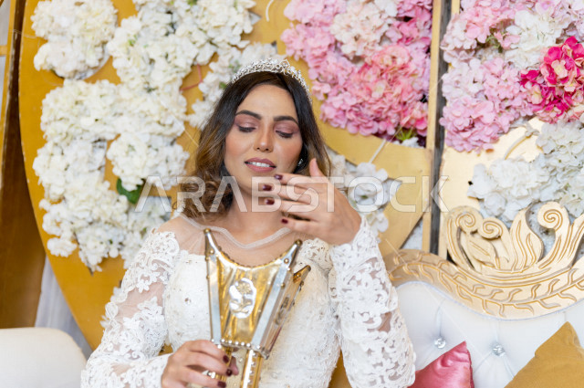 A Saudi Arabian bride sitting on the kosha, wearing incense and oud, wearing a white wedding suit, the night of life, occasions and weddings