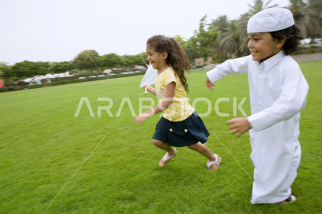 الاستمتاع بالركض في الطبيعة الخضراء في الهواء الطلق، أنشطه ترفيهية مسليه للأطفال، أخوان عربيان خليجيان اماراتيان يقومان بإصطياد الفراشات بواسطة شبكة الصيد، قضاء أوقات ممتعه في الحدائق العامه، ايماءات الفرح والسعاده.