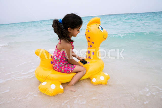 الأنشطة الترفيهية والفعاليات المسليه، الاستعداد لممارسة هواية السباحه، الاستمتاع والتسليه في أوقات الفراغ،  فتاه عربية خليجية اماراتية تجلس على عوامه السباحة في شاطئ البحر، زياره المنتجعات الساحلية السياحية في دول الخليج العربي، التنزه في الهواء الطلق