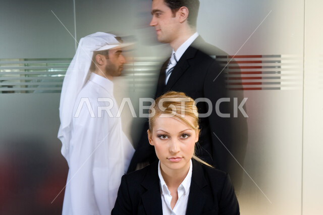 الأناقة والاهتمام  بالمظهر الخارجي  ، سيدة أعمال ترتدي البدلة الرسمية وتنظر إلى الكاميرا , تحركات وتنقل رجال الأعمال و الموظفين في مقر الشركة  , نظرات مليئة بالثقة بالنفس والطموح ، بيئة العمل الإماراتي ، خلفية جدار زجاجي . 