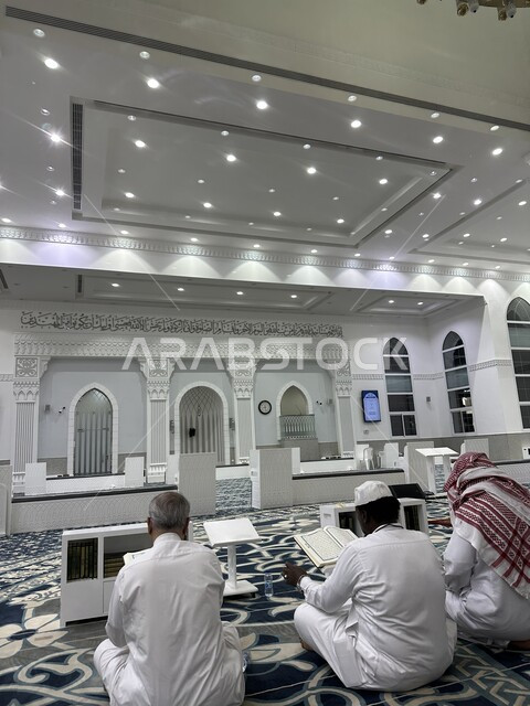 الفن الهندسي المعماري لمعالم مدينة جدة الاسلامية في السعودية، صورة من الخلف لمجموعه من المسلمين العرب الخليجيين السعوديين يجلسون داخل  مسجد الرحمة و يقومون بقراءة القرآن الكريم، التصميمات والديكورات الداخليه المتميزة، العبادة والتقرب إلى الله تعالى