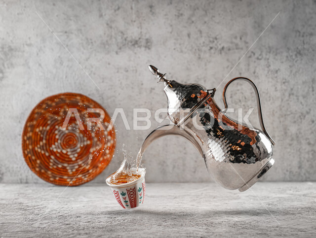 منتجات محليه وطنية, عادات وتقاليد العرب في شرب القهوة, صب القهوة العربية الساخنه في الفنجان الزجاجي, إكرام الضيف وحسن الاستقبال, الضيافة التقليديه في المملكة العربية السعودية, السلال اليدويه المنسوجة التراثية, خلفية رماديه