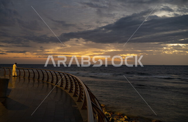 Landmarks of Jeddah Corniche on the Red Sea coast, Jeddah waterfront in western Saudi Arabia, a Saudi Gulf Arab man wearing a traditional dress looking at something at sunset, landscapes of famous tourist places
