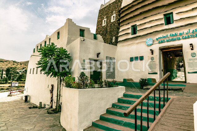 صورة مقربة لللواجهة الأمامية لقصور آل أبو نقطة المتحمي التاريخي في منطقة عسير ، الاستمتاع بالمناظر المتميزة من القلاع القديمة المطلة على ضفاف وادي طبب ،الشرفات والحواف العليا المطلية باللون الابيض ، معالم سياحية بارزة  في المملكة العربية السعودية .