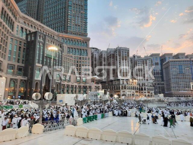 The arrival of Muslims from all over the world to Mecca, the geometric art of the architectural towers surrounding the Holy Mosque in Mecca, visitors to the Holy House of God in the outer courtyard, famous religious tourist attractions, the entry of worshipers into the Grand Mosque to perform rituals and worship and become closer to God.