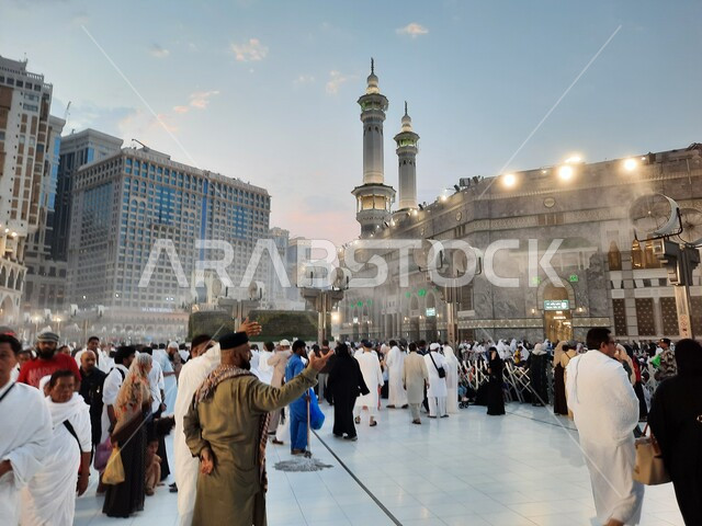 Famous religious tourist attractions, the geometric art of the architectural towers surrounding the Grand Mosque in Mecca, visitors to the Holy House of God in the outer courtyard, the arrival of Muslims from all over the world to Mecca, the entry of worshipers into the Grand Mosque to perform rituals and worship and get closer to God
