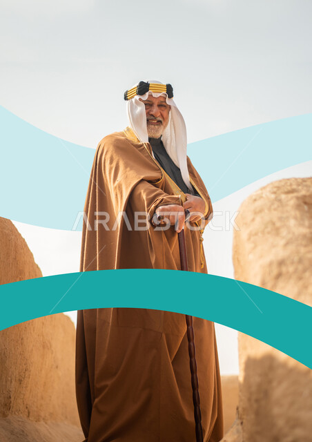 Commemoration of the Saudi Founding Day on February 22, pride and pride in belonging to the country, an elderly Saudi Gulf Arab man wearing a bisht and ghutra standing between the mud buildings and extending his hand forward and looking at the camera, the 93rd Saudi National Day on September 23, the founding of the first Saudi state 1727 AD
