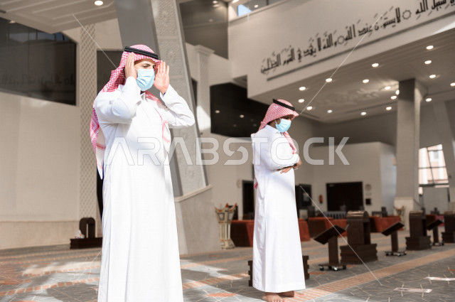 أداء فريضة الصلاه داخل المسجد، صلاه الجماعة لرجلان سعوديان يرتديان الكمامة ، يحافظان على التباعد بينهم ، الالتزام باجراءات الوقاية ، العبادة و التقرب الى الله
