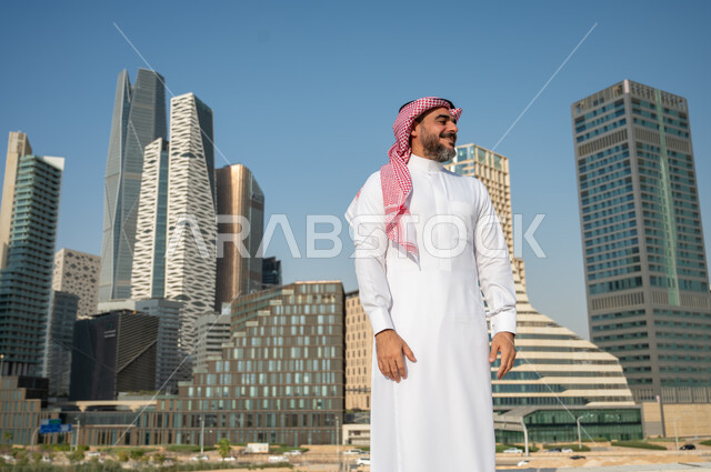 المباني المالية والمنشآت الإقتصادية، رجل عربي خليجي سعودي يرتدي الشماغ والثوب التقليدي بإيماءات وجه تدل على السعادة والفرح، الفن الهندسي المعماري للأبراج وناطحات السحاب في الرياض، النمو والتطور العمراني في السعودية، خلفية مركز الملك عبد الله المالي (كافد)