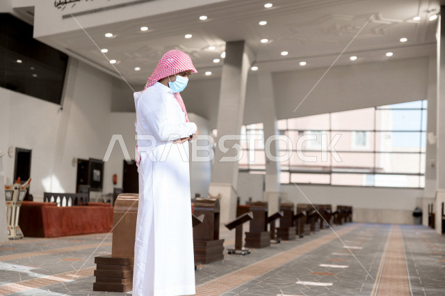 أداء فريضة الصلاه داخل المسجد، صلاه الجماعة لرجلان سعوديان يرتديان الكمامة ، يحافظان على التباعد بينهم ، الالتزام باجراءات الوقاية ، العبادة و التقرب الى الله