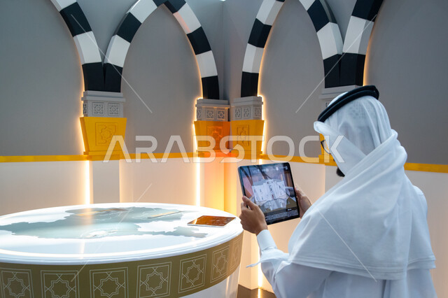 الفرص الاستثمارية في مكة المكرمة والمشاعر المقدسة، رجل عربي خليجي سعودي يستخدم التابلت داخل معرض سيتي سكيب العالمي، مركز الرياض للمعارض في بلدة ملهم في السعودية، رؤية سعودية مستقبلية 2030، الاستدامة والتخطيط المعماري لقطاع العقارات
