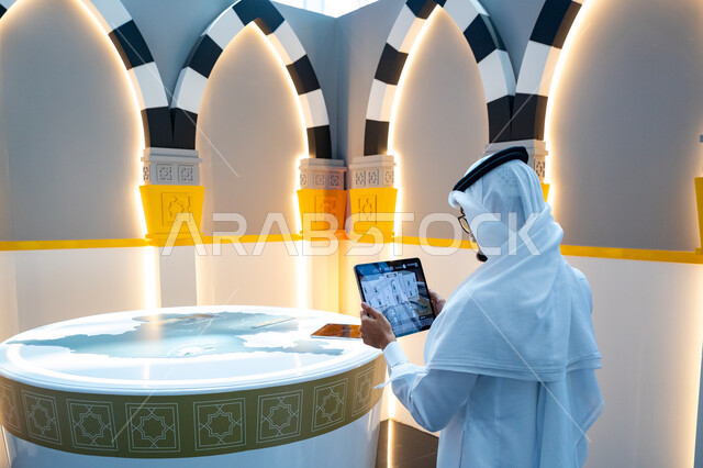 الفرص الاستثمارية في مكة المكرمة والمشاعر المقدسة، رجل عربي خليجي سعودي يستخدم التابلت داخل معرض سيتي سكيب العالمي، مركز الرياض للمعارض في بلدة ملهم في السعودية، رؤية سعودية مستقبلية 2030، الاستدامة والتخطيط المعماري لقطاع العقارات