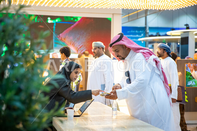 مندوبة تسويق عربية خليجية سعودية تقوم بالرد على استفسارات زوار معرض سيتي سكيب العالمي، الفرص الاستثمارية في المشاريع السكنية والتجارية والفندقية، مركز الرياض للمعارض في بلدة ملهم في السعودية، الاستدامة والتخطيط المعماري العقارات، رؤية مستقبلية 2030