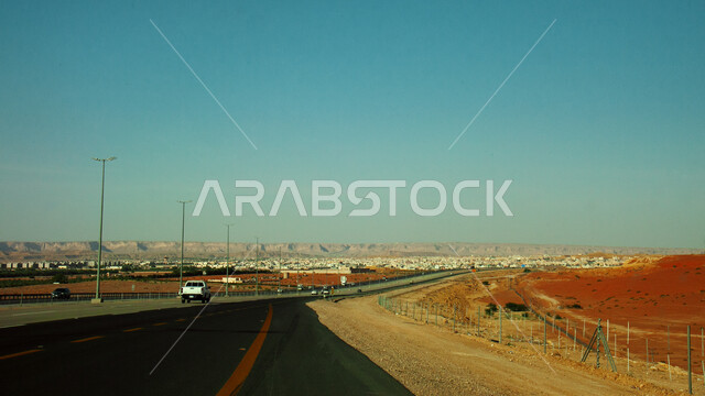 The highway in the middle of the desert, the asphalt highway between the sand dunes leading to Al-Muzahmiyah Governorate, the outskirts of the city of Riyadh in the Kingdom of Saudi Arabia, the city’s view of the Najd Plateau