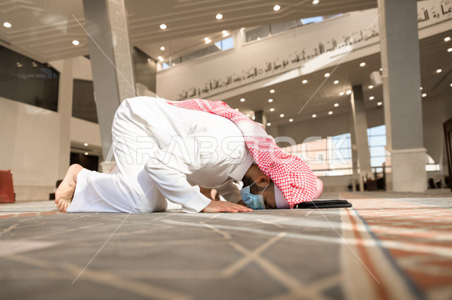 أداء فريضة الصلاه داخل المسجد، رجل سعودي يصلي و يرتدي الكمامة  ، الالتزام باجراءات الوقاية ، العبادة و التقرب الى الله