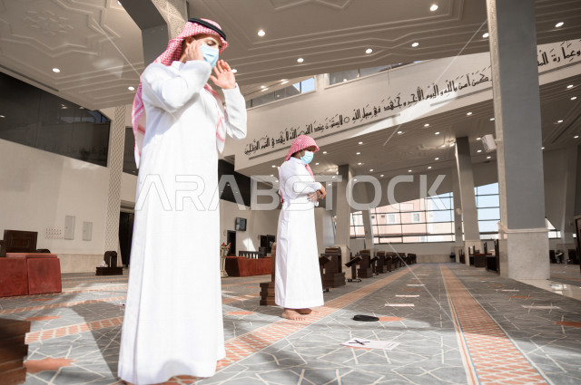 أداء فريضة الصلاه داخل المسجد، صلاه الجماعة لرجلان سعوديان يرتديان الكمامة ، يحافظان على التباعد بينهم ، الالتزام باجراءات الوقاية ، العبادة و التقرب الى الله