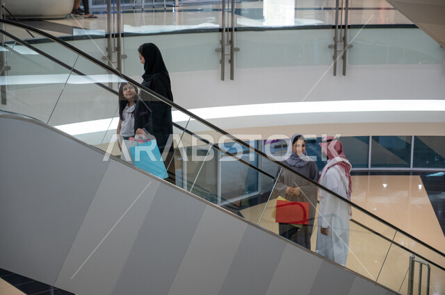 التجول والصعود عبر السلالم والأدراج الكهربائيه, مجموعه من المواطنين العرب الخليجين السعوديين يقومون باستخدام الدرج الكهربائي, متعه التسوق والشراء في المولات السعوديه, الاستمتاع في قضاء وقت ممتع مع العائله, شراء المستلزمات والهدايا