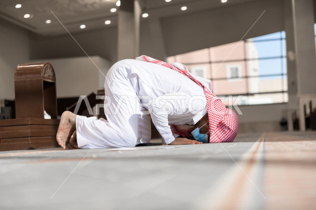 أداء فريضة الصلاه داخل المسجد، رجل سعودي يصلي و يرتدي الكمامة  ، الالتزام باجراءات الوقاية ، العبادة و التقرب الى الله