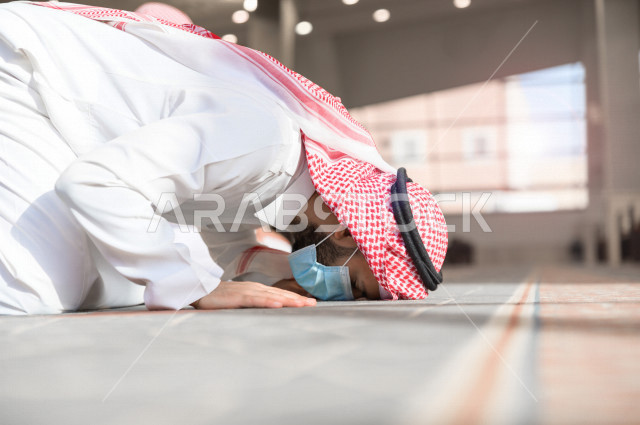 أداء فريضة الصلاه داخل المسجد، رجل سعودي يصلي و يرتدي الكمامة  ، الالتزام باجراءات الوقاية ، العبادة و التقرب الى الله