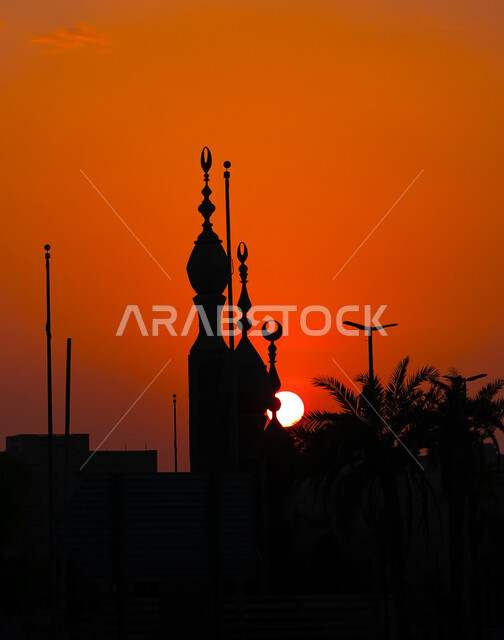 Silhouette of a mosque structure in the city of Jeddah in the Kingdom of Saudi Arabia, view of the sunset in the sky behind the minarets, sacred Islamic religious places and landmarks, worship and closeness to God, nature background