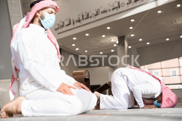 أداء فريضة الصلاه داخل المسجد، صلاه الجماعة لرجلان سعوديان يرتديان الكمامة ، يحافظان على التباعد بينهم ، الالتزام باجراءات الوقاية ، العبادة و التقرب الى الله