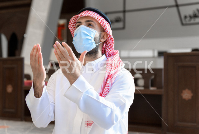A Saudi Muslim man inside the mosque, raises his hands up and prays to God, beseech God and ask for forgiveness, worship and draw close to God