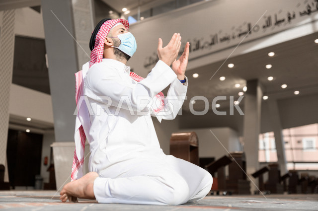 A Saudi Muslim man inside the mosque, raises his hands up and prays to God, beseech God and ask for forgiveness, worship and draw close to God