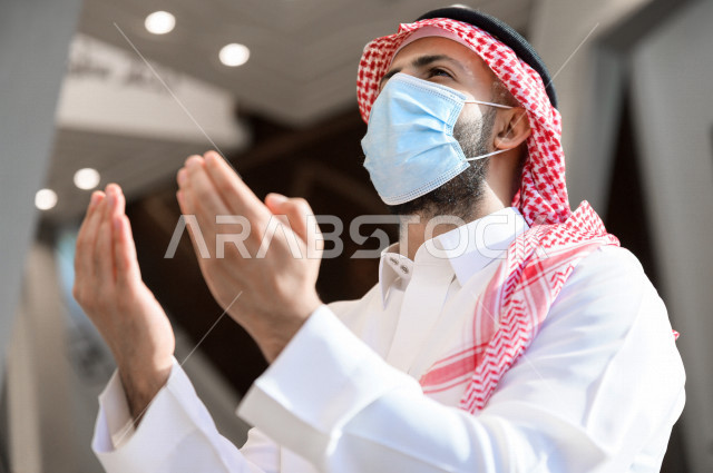 رجل سعودي مسلم  داخل المسجد ، يرفع يديه لأعلى و يدعو الله ، التضرع لله و طلب المغفرة  ، العبادة و التقرب الى الله 