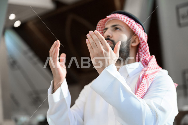 A Saudi Muslim man inside the mosque, raises his hands up and prays to God, beseech God and ask for forgiveness, worship and draw close to God