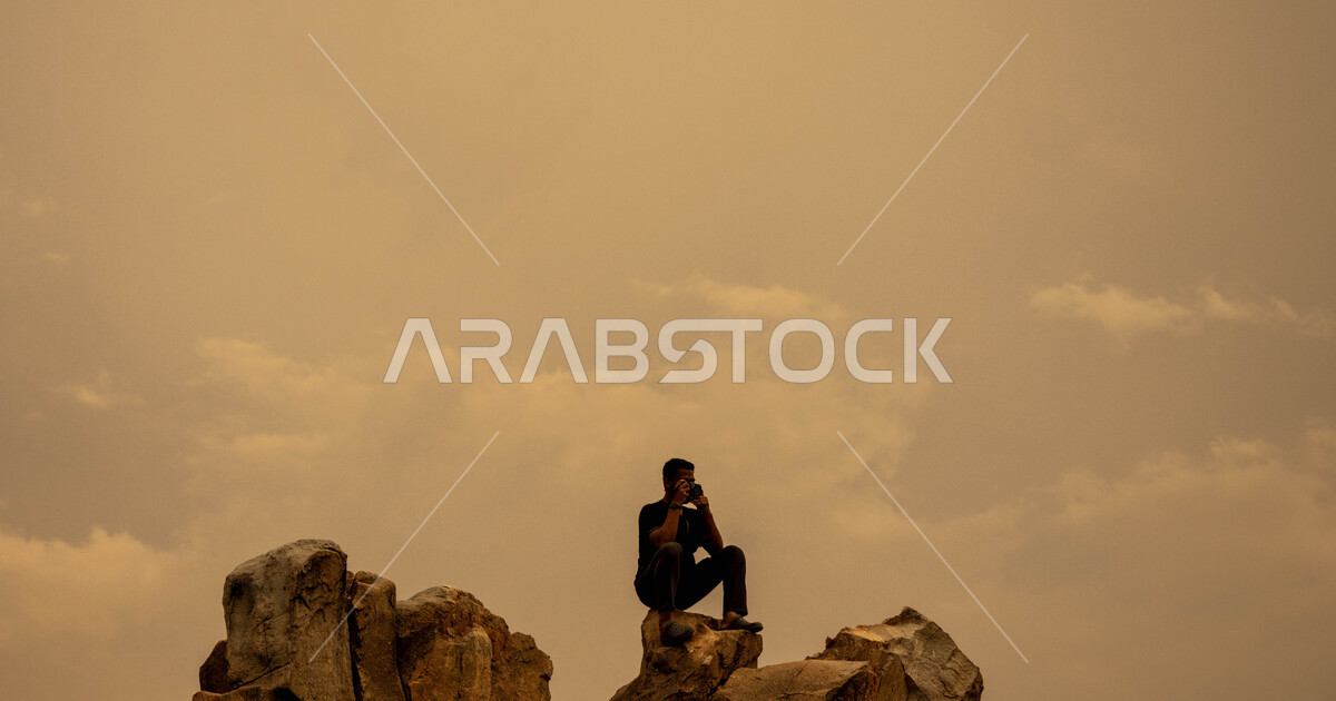 A young man sitting on top of a rocky mountain in the village of Al ...