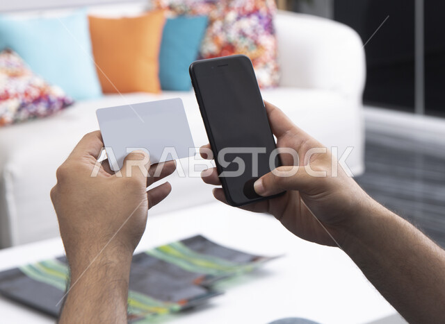 إجراء مكالمة هاتفية , استخدام حاسة اللمس بالتقنيات الحديثة ,رجل عربي خليجي سعودي  يحمل بيده جهاز الهاتف المحمول ، ايماءات يدين بالنقر بالاصبع على الشاشة ،  محاولة الاتصال برقم من خلال الكارد ,  البحث عن عمل .