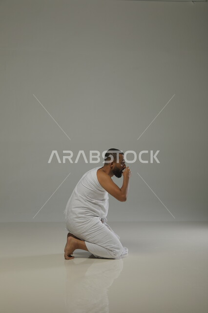 الشرب والارتواء من ماء زمزم ، الدعاء والعباده والتقرب الى الله، بورتريه جانبي لرجل مسلم عربي سعودي خليجي يرتدي ملابس الاحرام يقوم بآداء فريضة الحج، موسم العمرة في شهر رمضان المبارك، خلفية رمادية