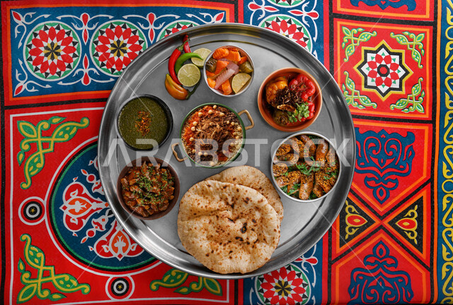 أرغفة الخبز الطازج على مائدة متنوعة من المأكولات العربية ,  صورة من الأعلى لصحون من الأطعمة  التقليدية كشري وملوخية وحمام محشي ,وصفات وأطباق طعام شعبية , وجبة الغداء في المطاعم والمطابخ , خلفية مزخرفة