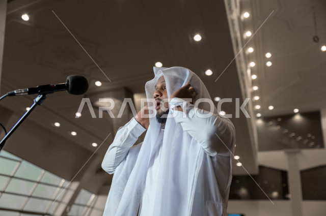 إمام مسجد سعودي خليجي في احدى المساجد بالمملكة العربية السعودية يؤذن بالمصليين على المنبر ، يقيم الصلاه على المصلين  ، دور أئمة المساجد والخطباء عظيم
