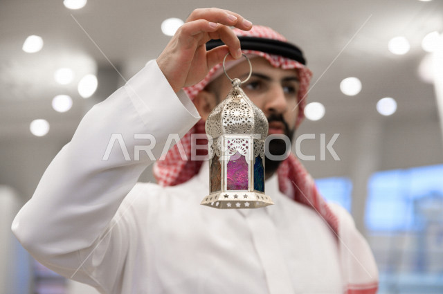رجل سعودي خليجي مسلم داخل احدى المساجد في المملكة العربية السعودية ،يحمل بيده فانوس ملون ، فانوس رمضان ،  ،العبادة و التقرب الى الله 