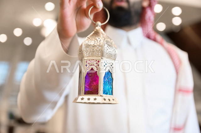 رجل سعودي خليجي مسلم داخل احدى المساجد في المملكة العربية السعودية ،يحمل بيده فانوس ملون ، فانوس رمضان ،  ،العبادة و التقرب الى الله 