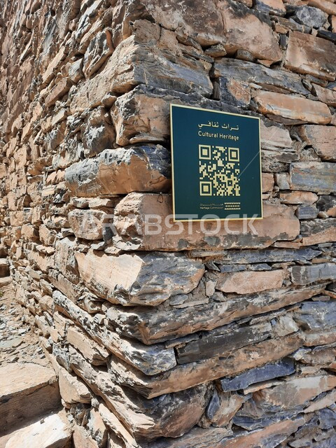 Tourist guide to the archaeological village, a close-up of an information board containing a barcode of cultural information about the historic heritage village of Dhi Al-Ain in the Al-Baha region, the famous fortified tourist attractions in Saudi Arabia, interest in mountainous areas to attract tourists from all over the world
