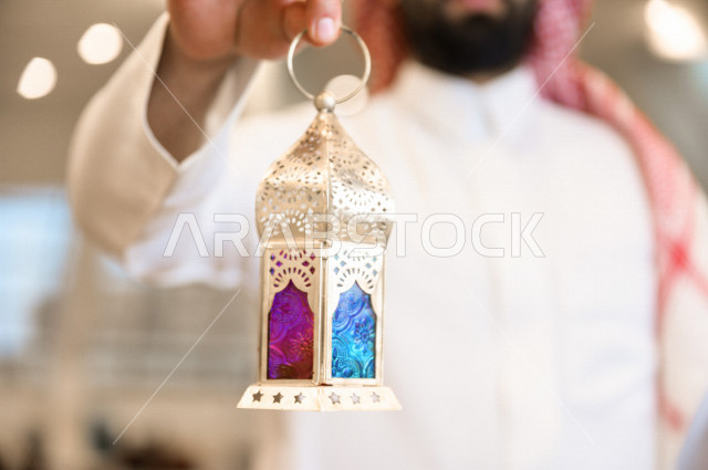 رجل سعودي خليجي مسلم داخل احدى المساجد في المملكة العربية السعودية ،يحمل بيده فانوس ملون ، فانوس رمضان ،  ،العبادة و التقرب الى الله 