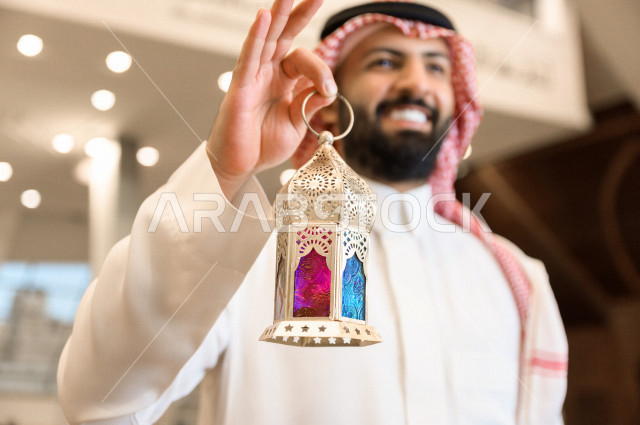 رجل سعودي خليجي مسلم داخل احدى المساجد في المملكة العربية السعودية ،يحمل بيده فانوس ملون ، فانوس رمضان ،  ،العبادة و التقرب الى الله 