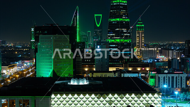 Urban growth and development in the Kingdom of Saudi Arabia, skyscrapers and residential and commercial towers at night time illuminated in green, famous tourist attractions in the city of Riyadh, architectural engineering art of buildings and facilities and interest in the country’s infrastructure