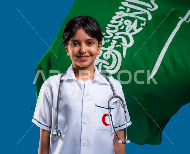 التعبير عن الولاء للدولة في اليوم الوطني السعودي 23 سبتمبر, صورة مقربة لفتاة عربية خليجية سعودية مبتسمة ترتدي المعطف الطبي الأبيض وسماعة الطبيب تحلم أن تصبح طبيبة طوارئ وإسعاف, يوم العلم 11 مارس, مفهوم الرعاية الصحية والطب, أحلام وأمنيات مستقبلية, خلفية زرقاء