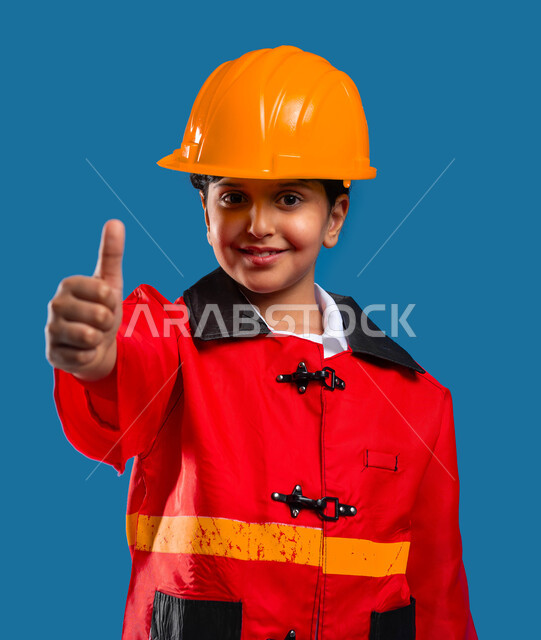 أهداف وطموحات مستقبلية, بورتريه مقرب لفتاة عربية خليجية سعودية مبتسمة ترتدي القبعة وسترة الحماية ترفع إصبعها الإبهام بالموافقة والرضى, التطوع بفرق الانقاذ, الدفاع المدني وشغف مساعده الناس, خلفية زرقاء
