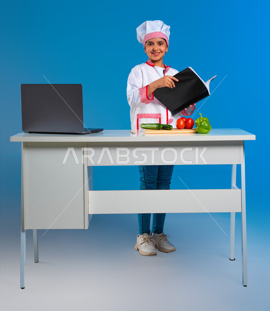 Professionalizing the profession of cooking, childhood wishes and dreams, a portrait of a Saudi Arabian Gulf girl dressed as a cook, holding a book in her hand and looking at the camera with a smile, applying food recipes from cookbooks, the skill of innovation, taste and learning the arts of eating, blue background