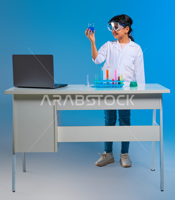 أبحاث علمية في معمل الكيمياء، اجراء تجارب وتفاعلات كيميائيه حيويه في المختبر,، بورتريه لفتاة عربية خليجية سعودية ترتدي معطف أبيض وتستخدم انابيب الاختبار، أمنية الحصول على مهنة الباحثة الكيميائية، خلفية زرقاء