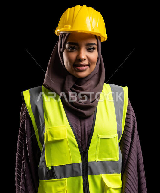 الاهتمام بشؤون العمل, المشاريع الهندسية والإعمار بالمملكة, بورتريه مقرب لمهندسة عربية خليجية سعودية مبتسمة ترتدي سترة الحماية والخوذة تنظر إلى الكاميرا بإيماءات السرور, وظائف ومهن نسائية, خلفية سوداء