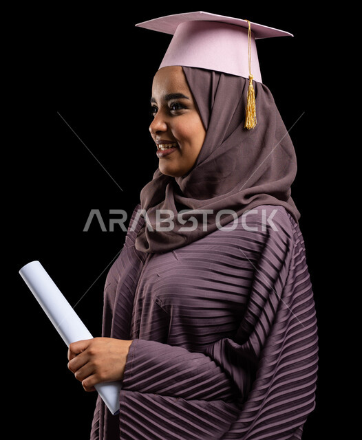 Graduation and exploring job opportunities, the quality of education in Saudi universities, a close-up portrait of a Saudi Arabian Gulf female university graduate wearing an abaya and graduation cap and holding a graduation certificate in her hand, celebrations of achieving the dream of success at university, black background
